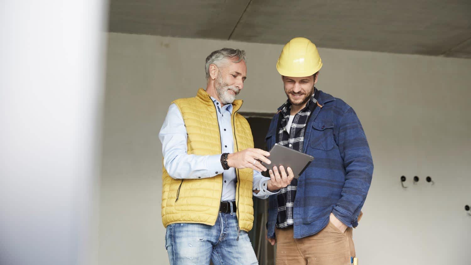Architect and worker sharing tablet on a construction site