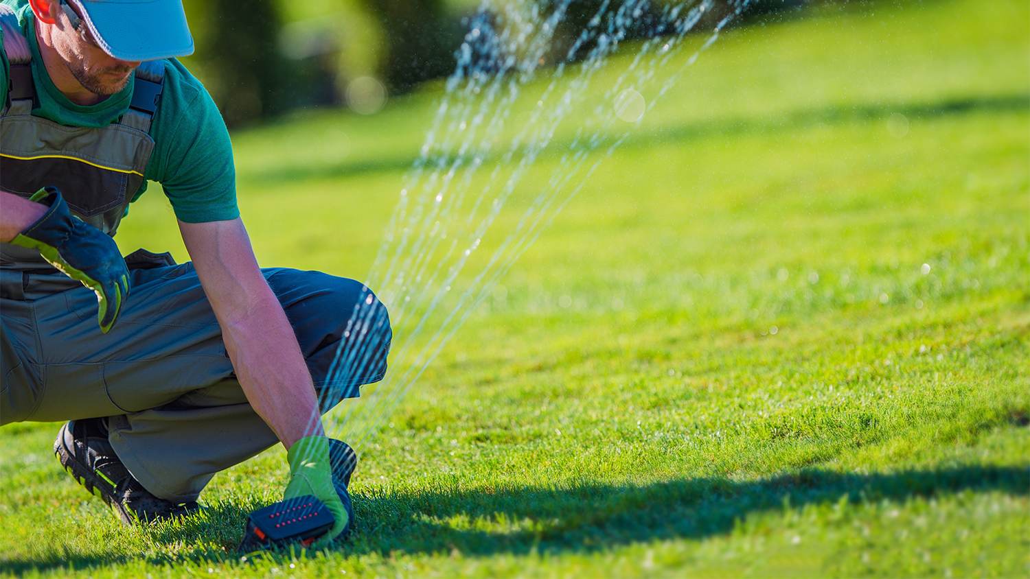 worker adjusting lawn sprinkler