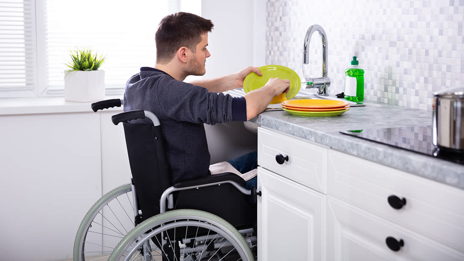 man in wheelchair washing dishes