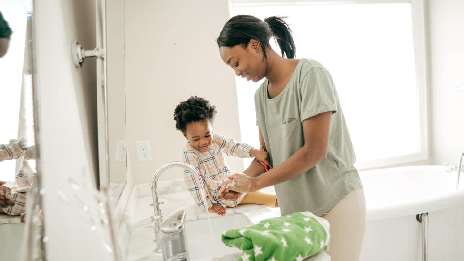 A mother washing her hands next to her daughter