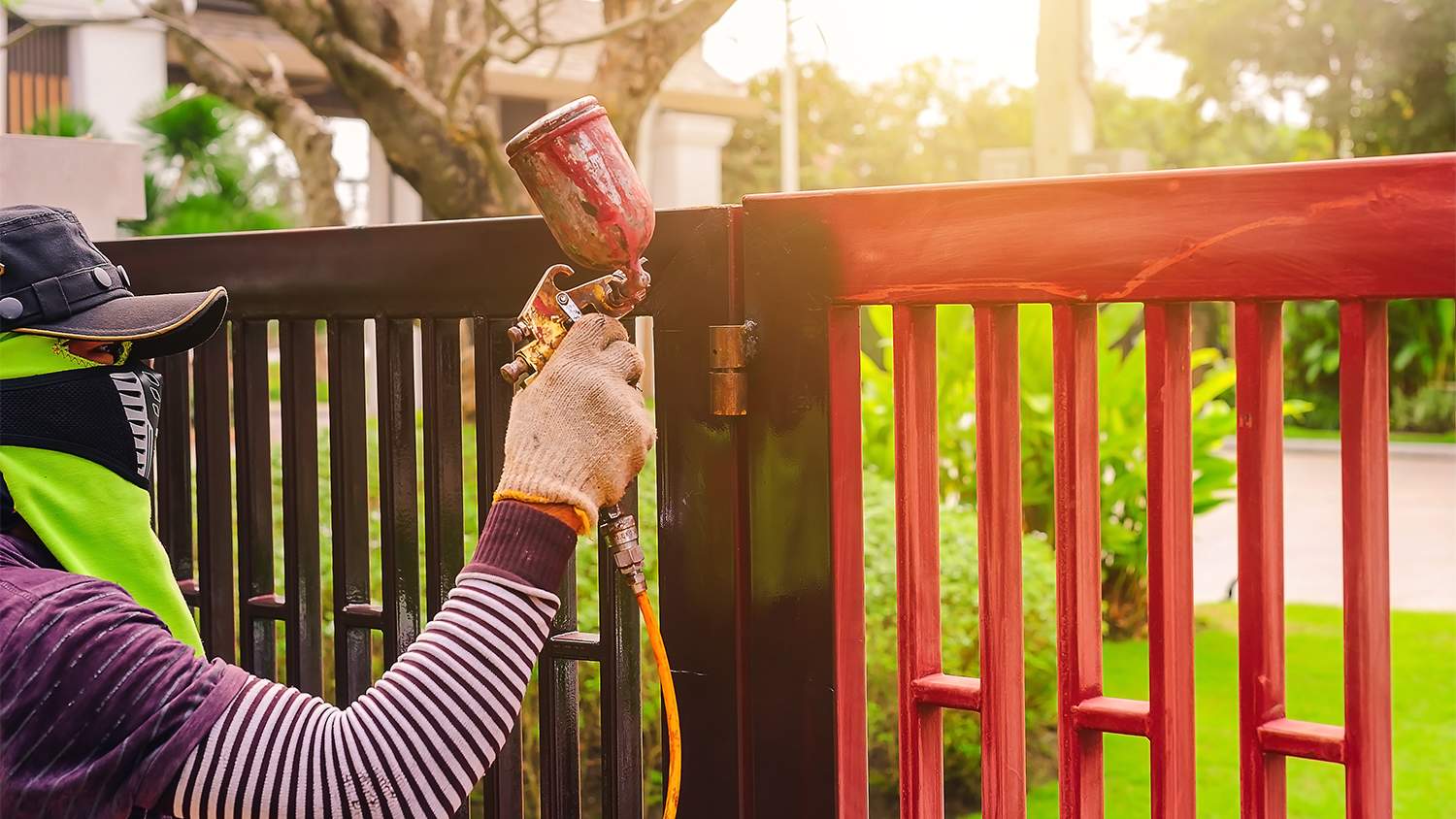 man spray painting metal gate