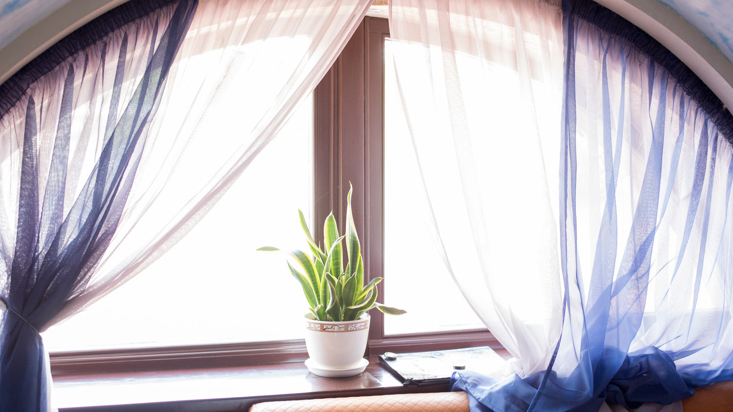 A wooden arched window with a blue curtain