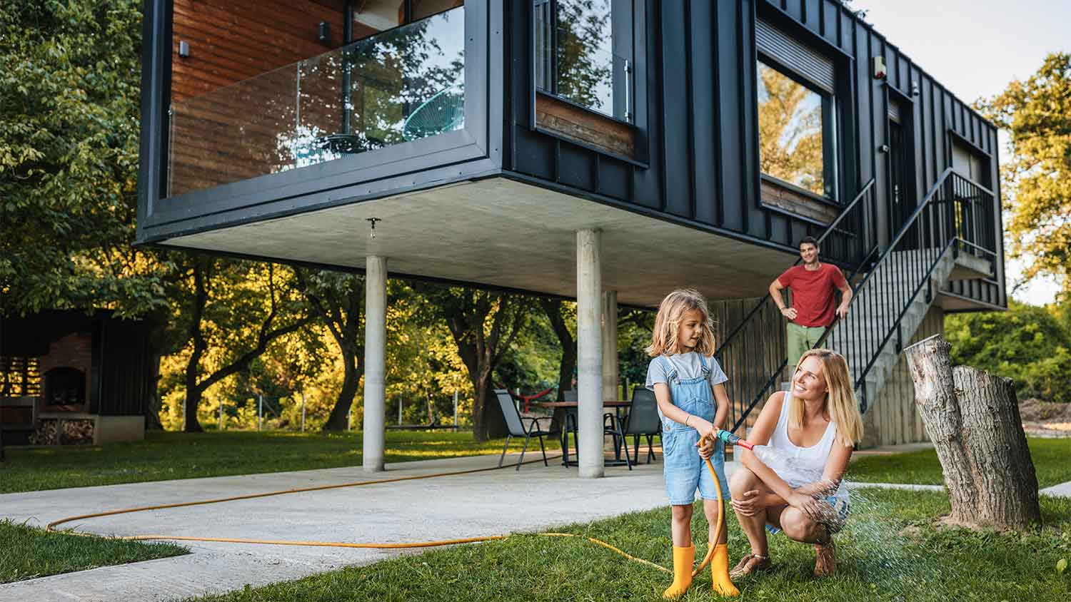 Family watering grass outside tiny house