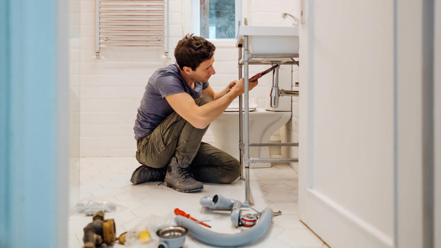 A plumber fixing a leak under the sink