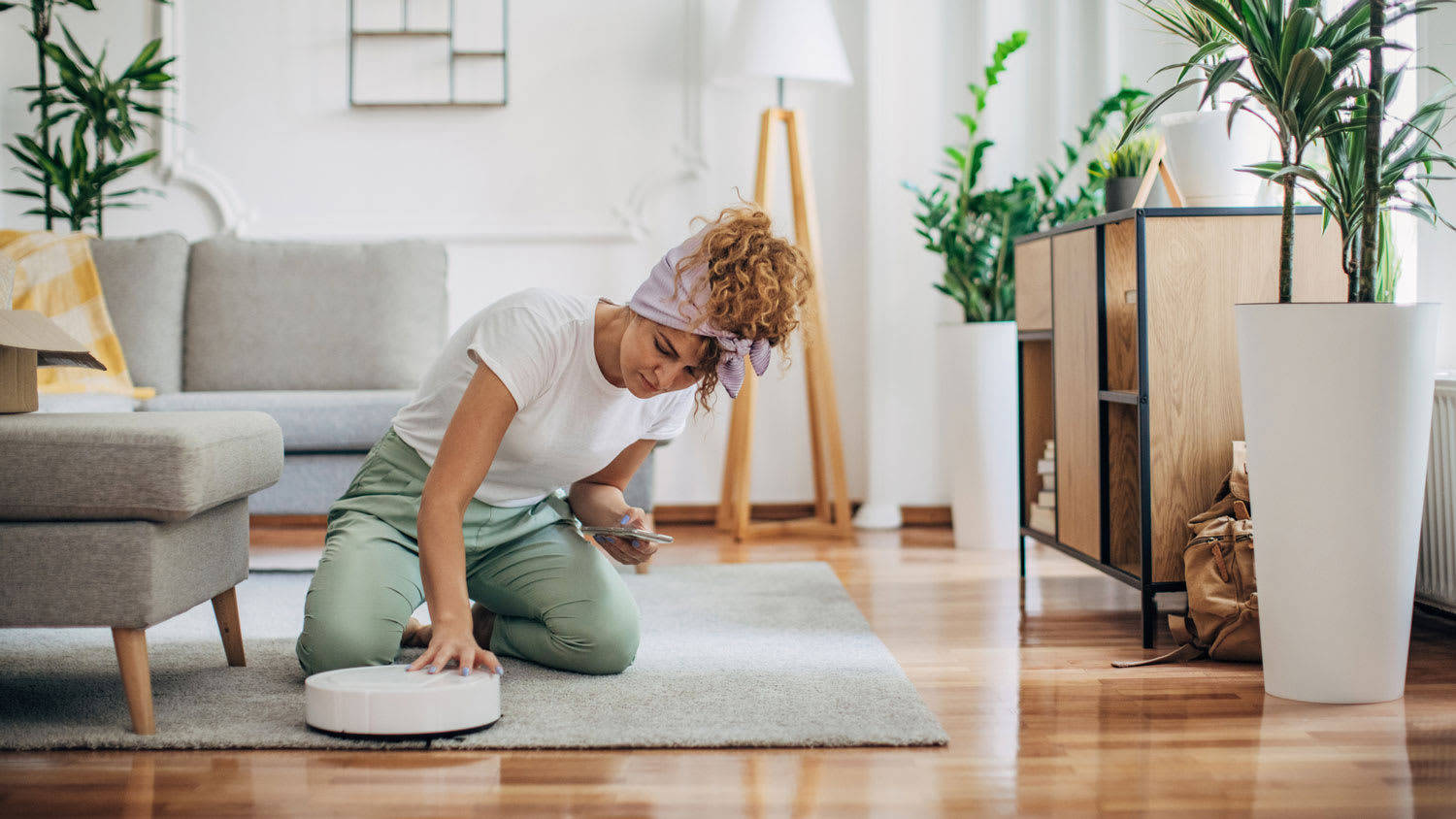 A woman turning on a robot vacuum