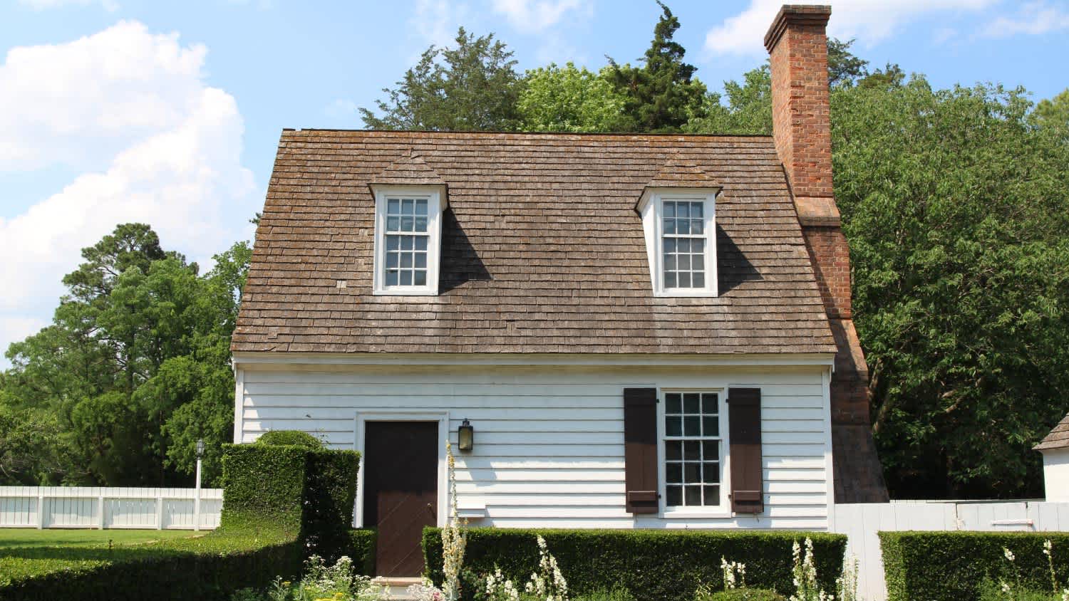 A front view of a white colonial style house with chimney