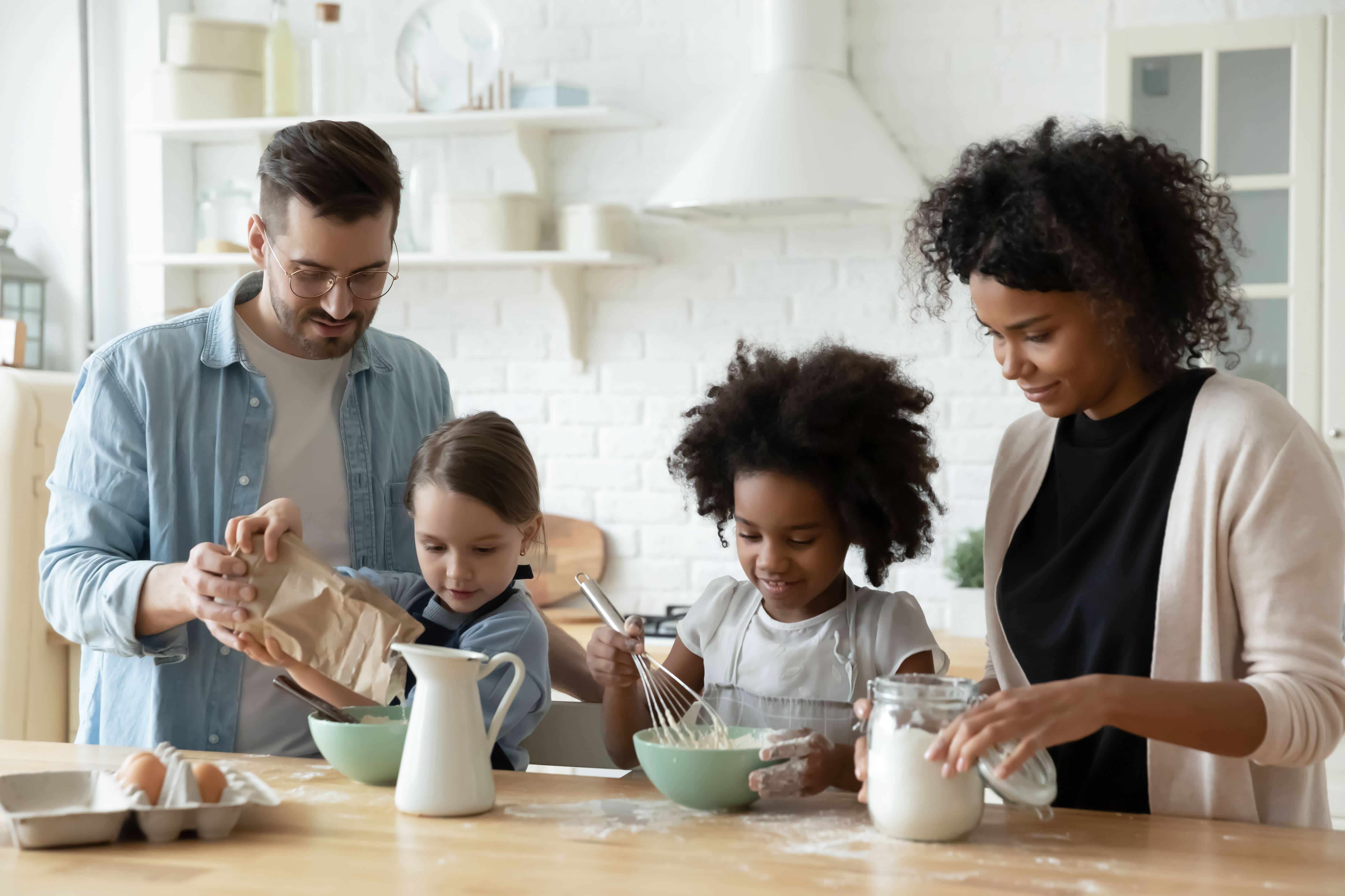 Family of four mixes ingredients atop a butcher block countertop island