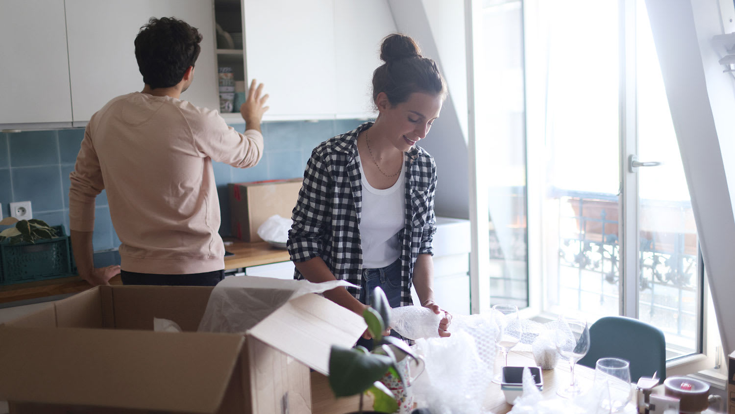 Couple packing tableware in cardboard boxes