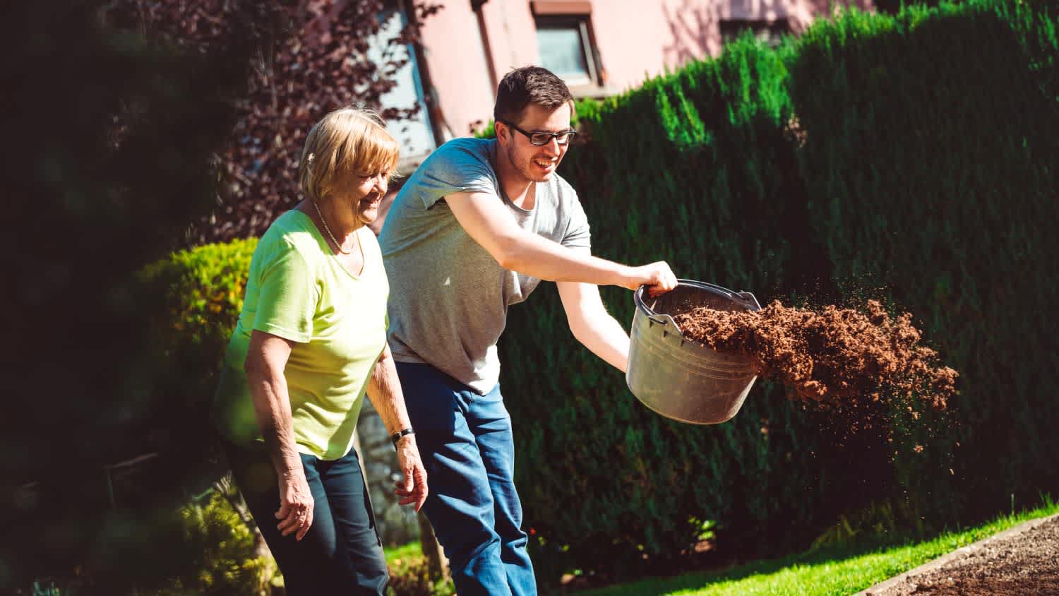 A woman and her grandson preparing her garden for planting plants