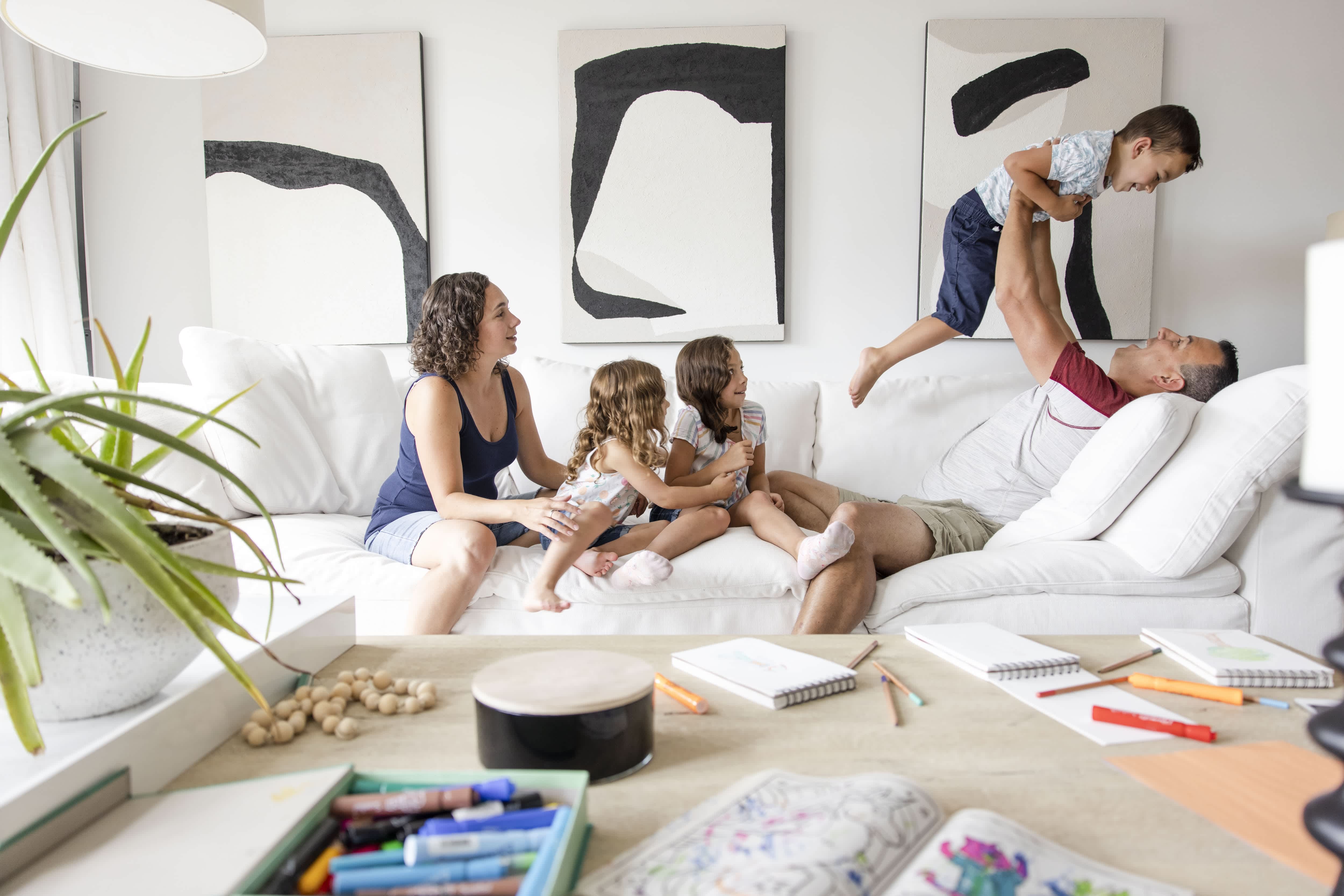 Family smiling and playing on living room sofa
