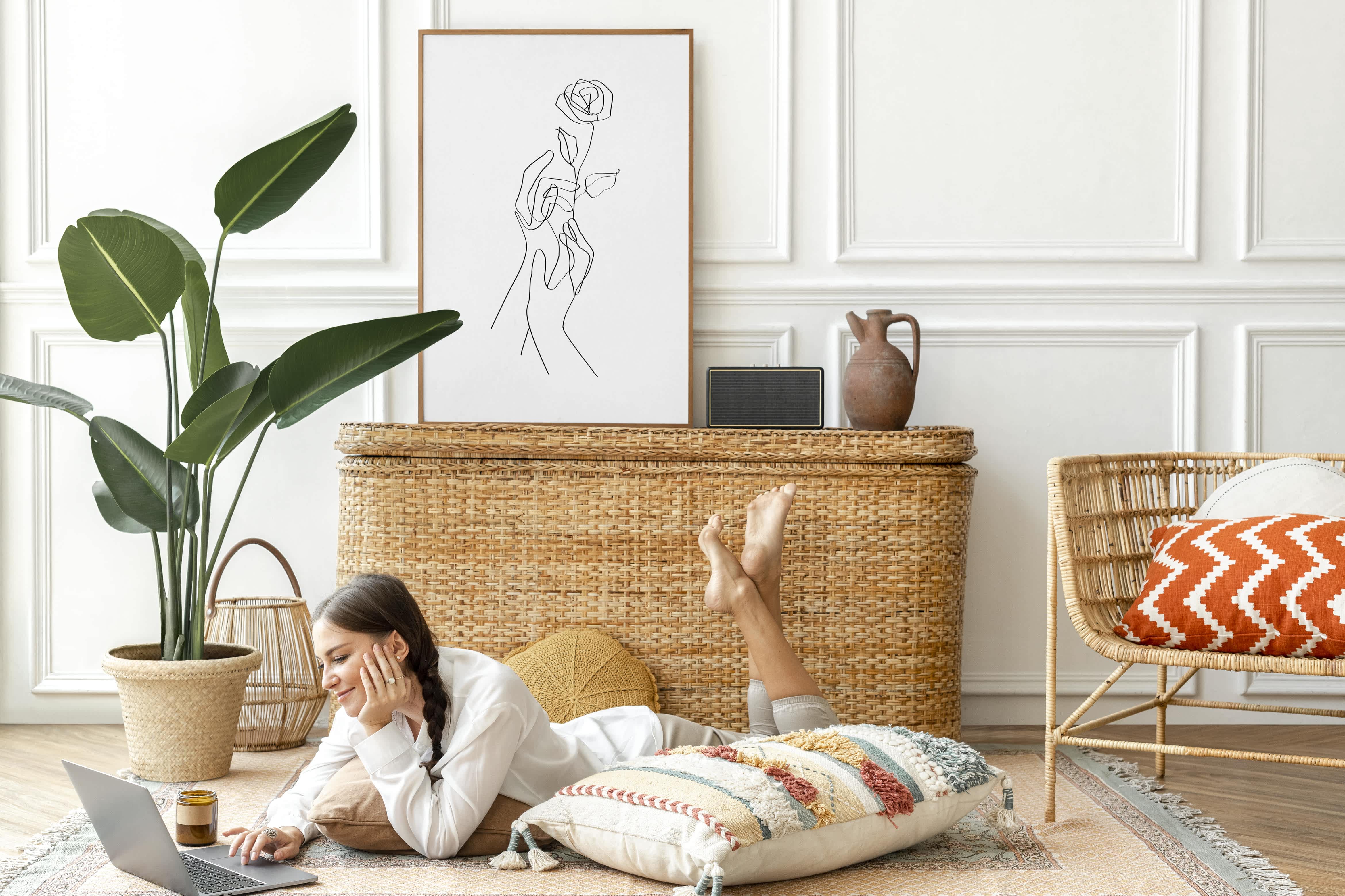 Woman laying on floor surfing laptop in front of rattan storage container