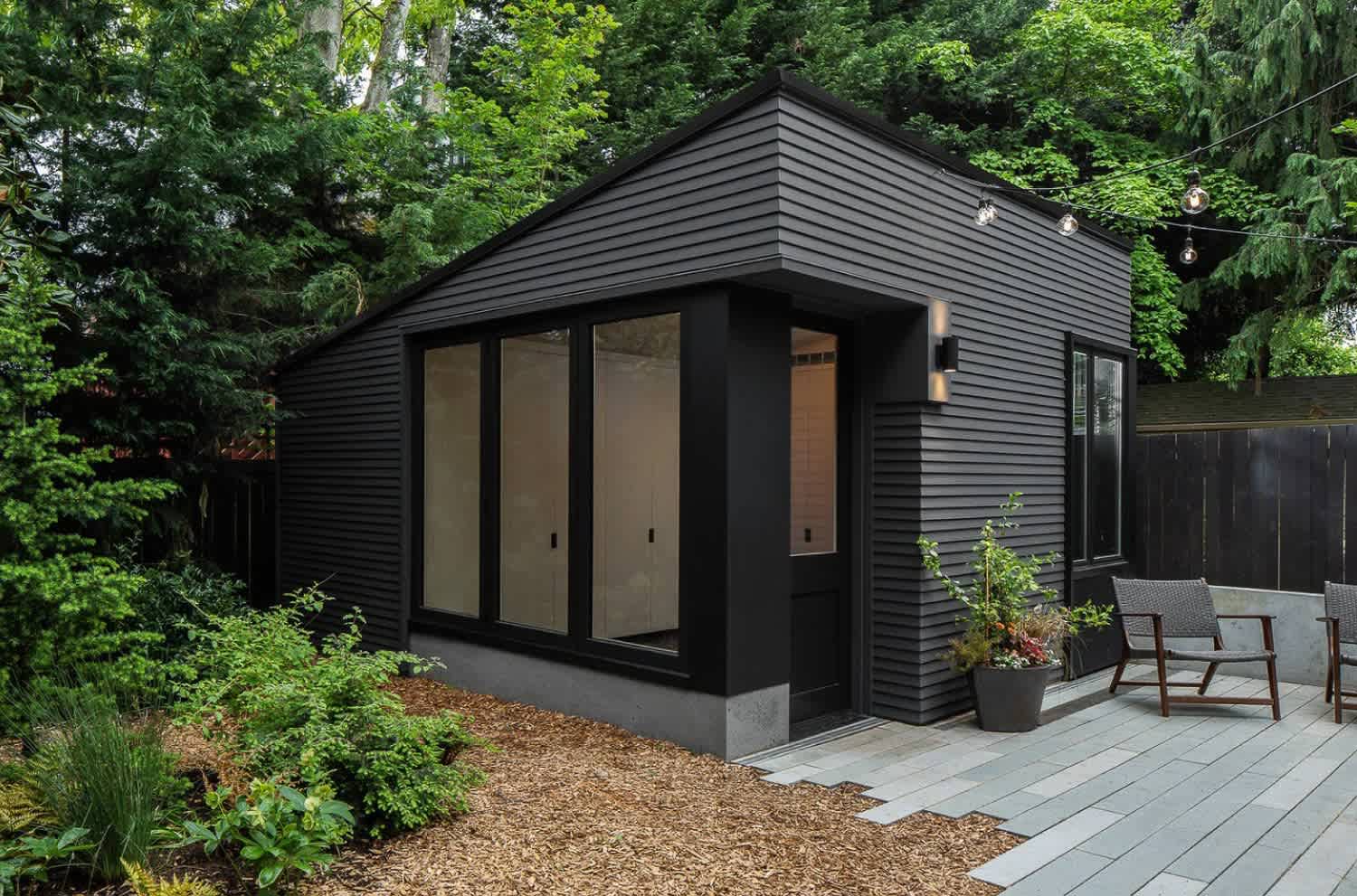 A garden shed with black siding