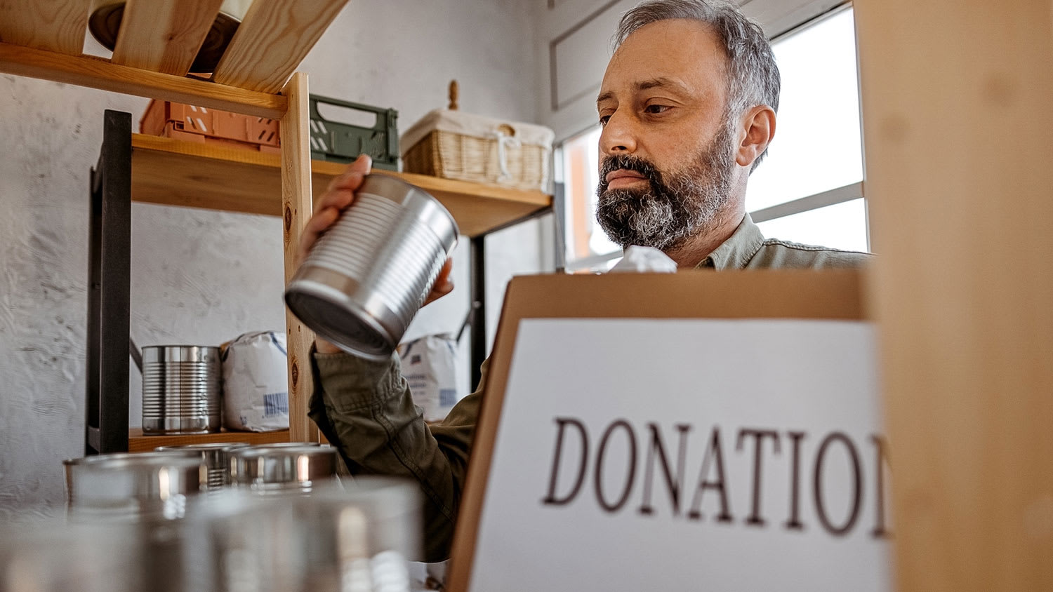 Man putting canned food in a donation box