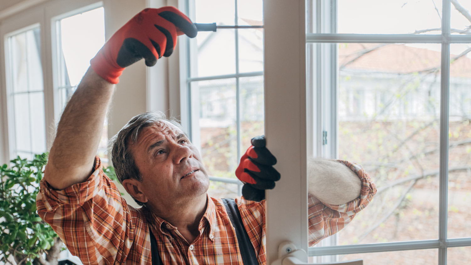 A senior man removing a window by using a screwdriver