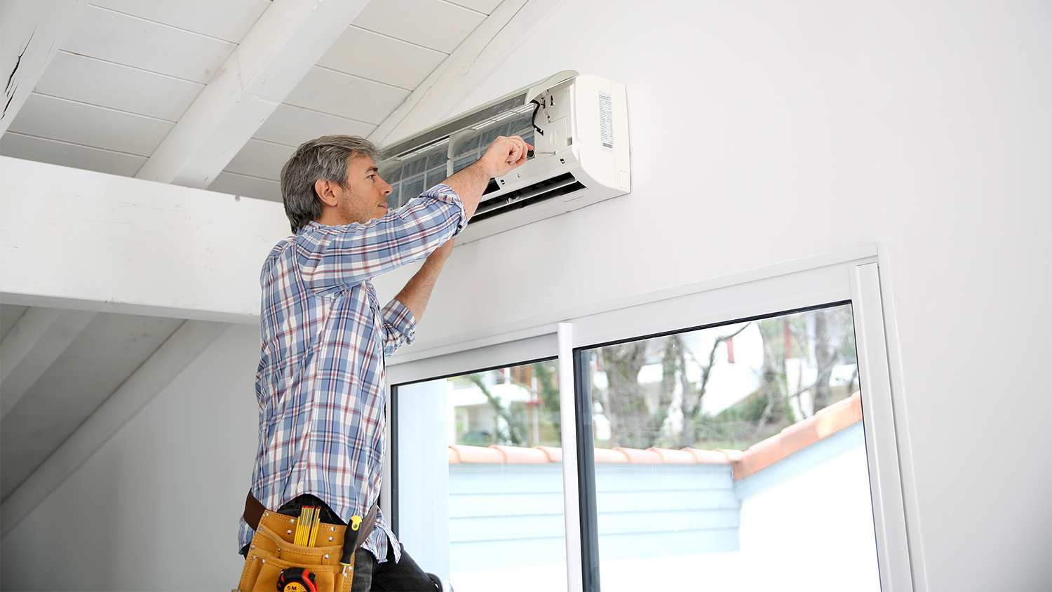 repairman fixing/ cleaning ac unit in home