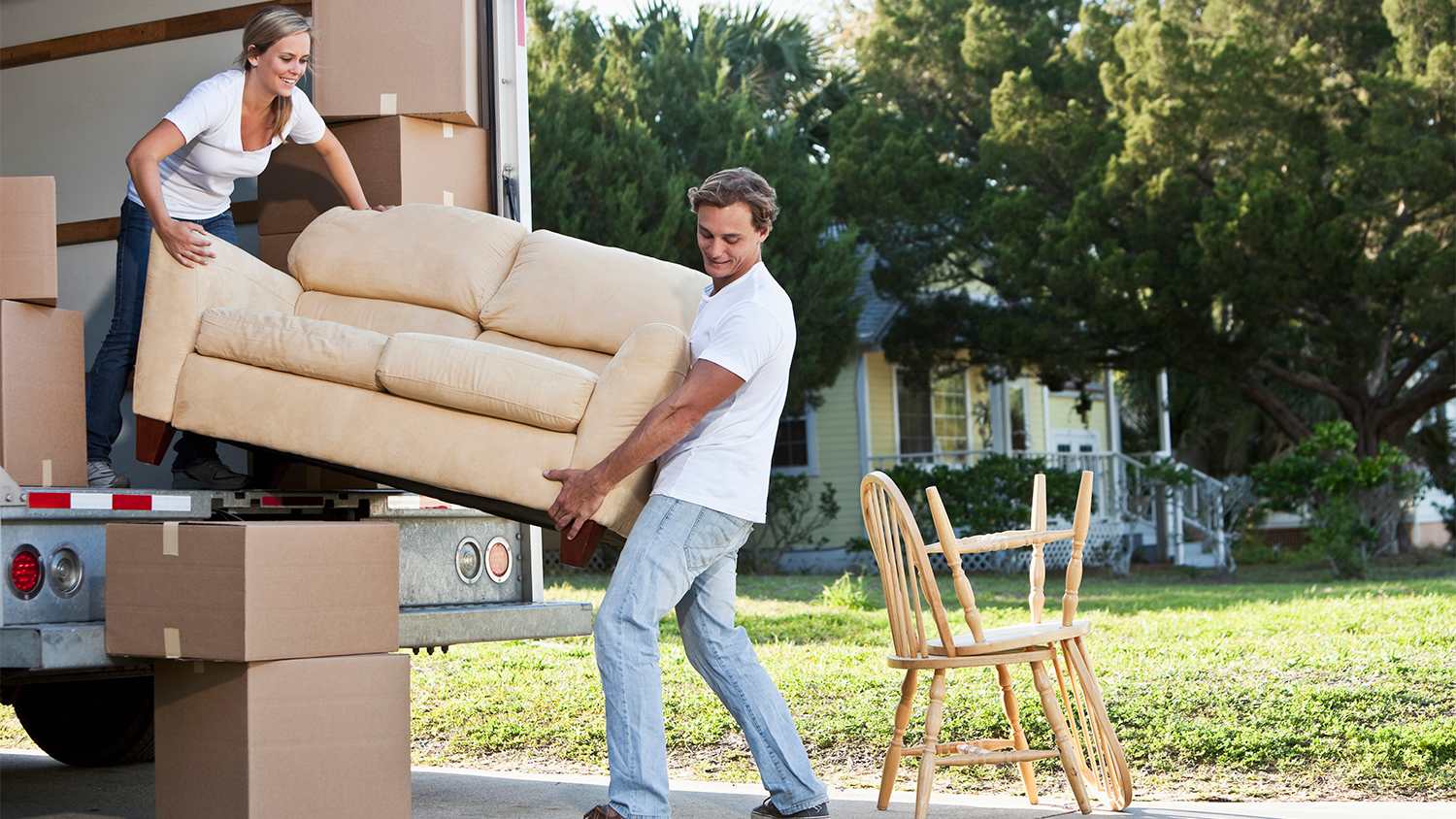 couple carrying couch into truck