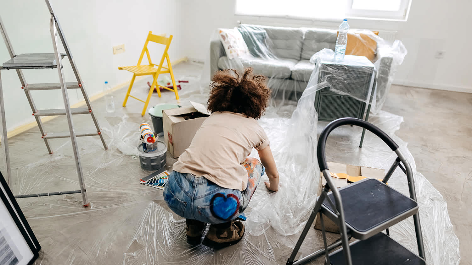 woman protecting surfaces in apartment before painting