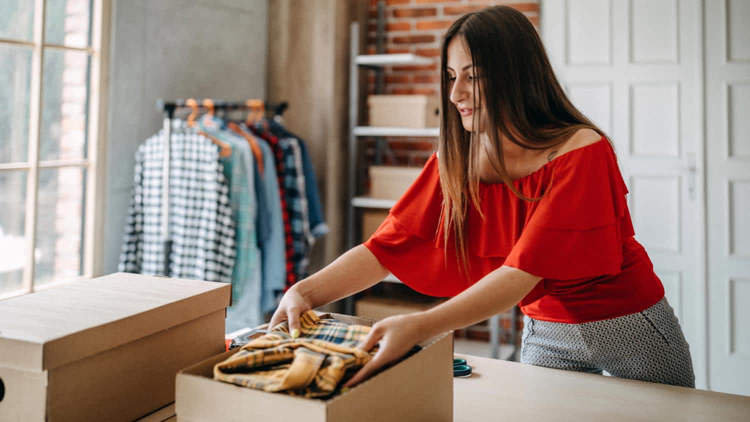 A woman packing shirts in a cardboard box