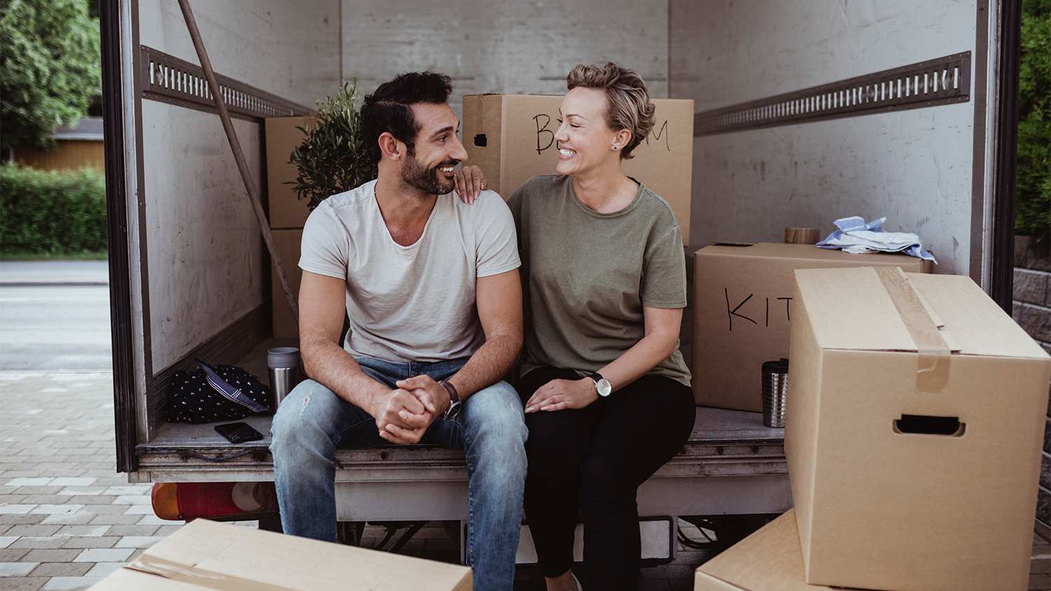 couple sitting on moving truck loading boxes