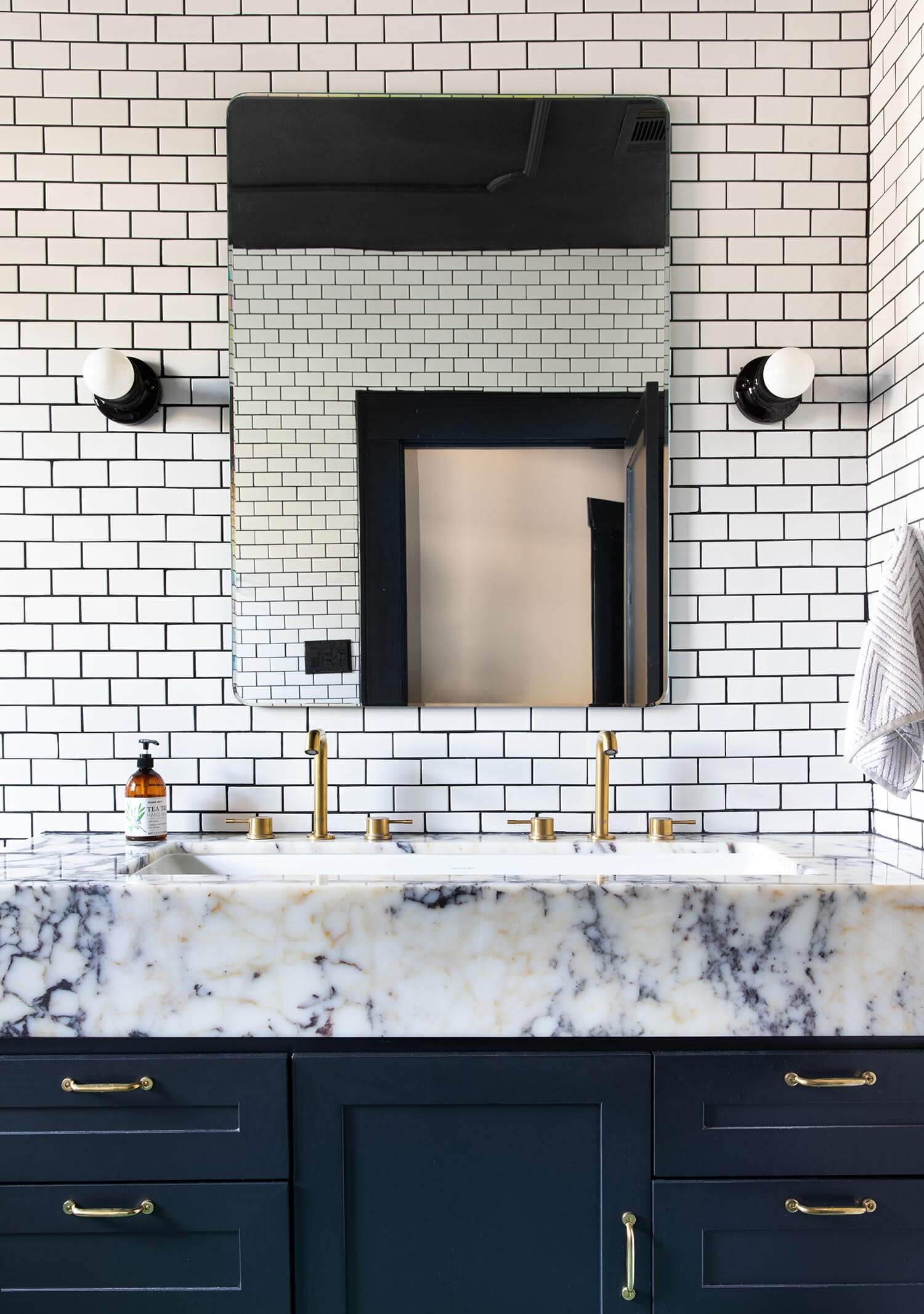 A blue bathroom vanity with white tiles and black grout