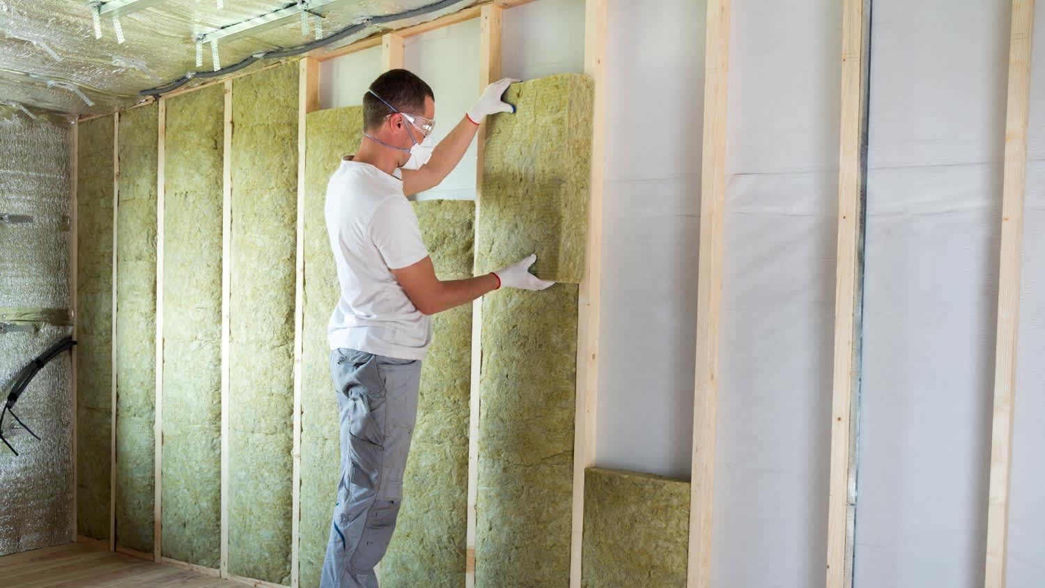 A worker installing mineral wool insulation