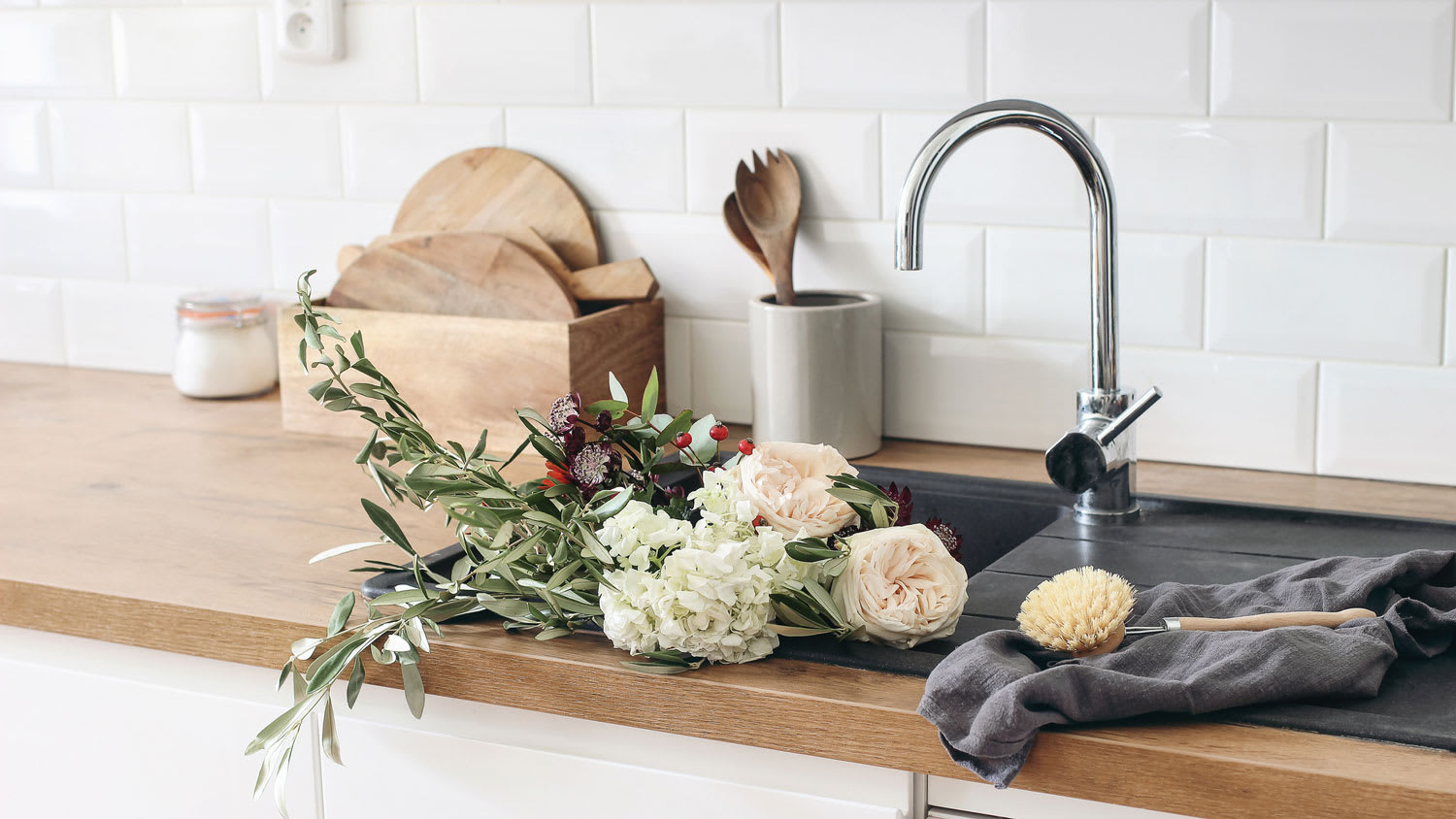 A kitchen with a black sink and subway tiles