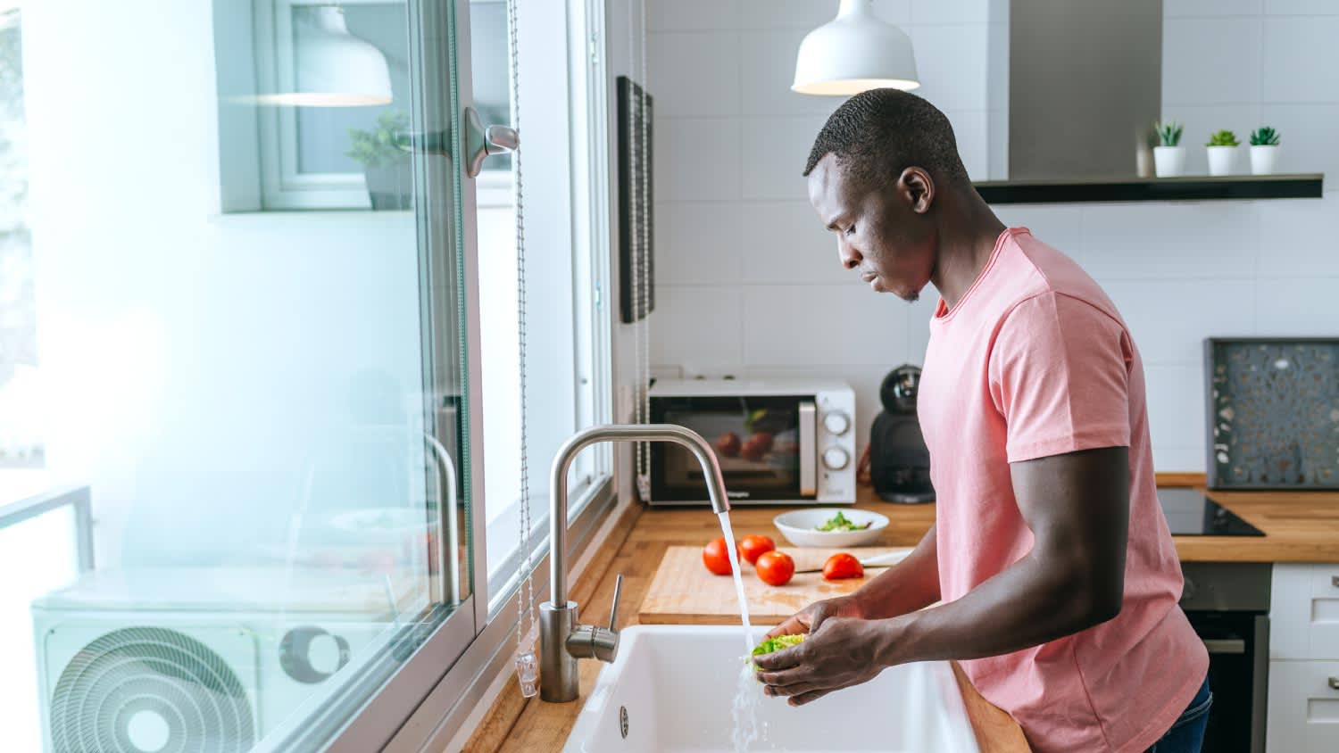 A man washing lettuce in kitchen
