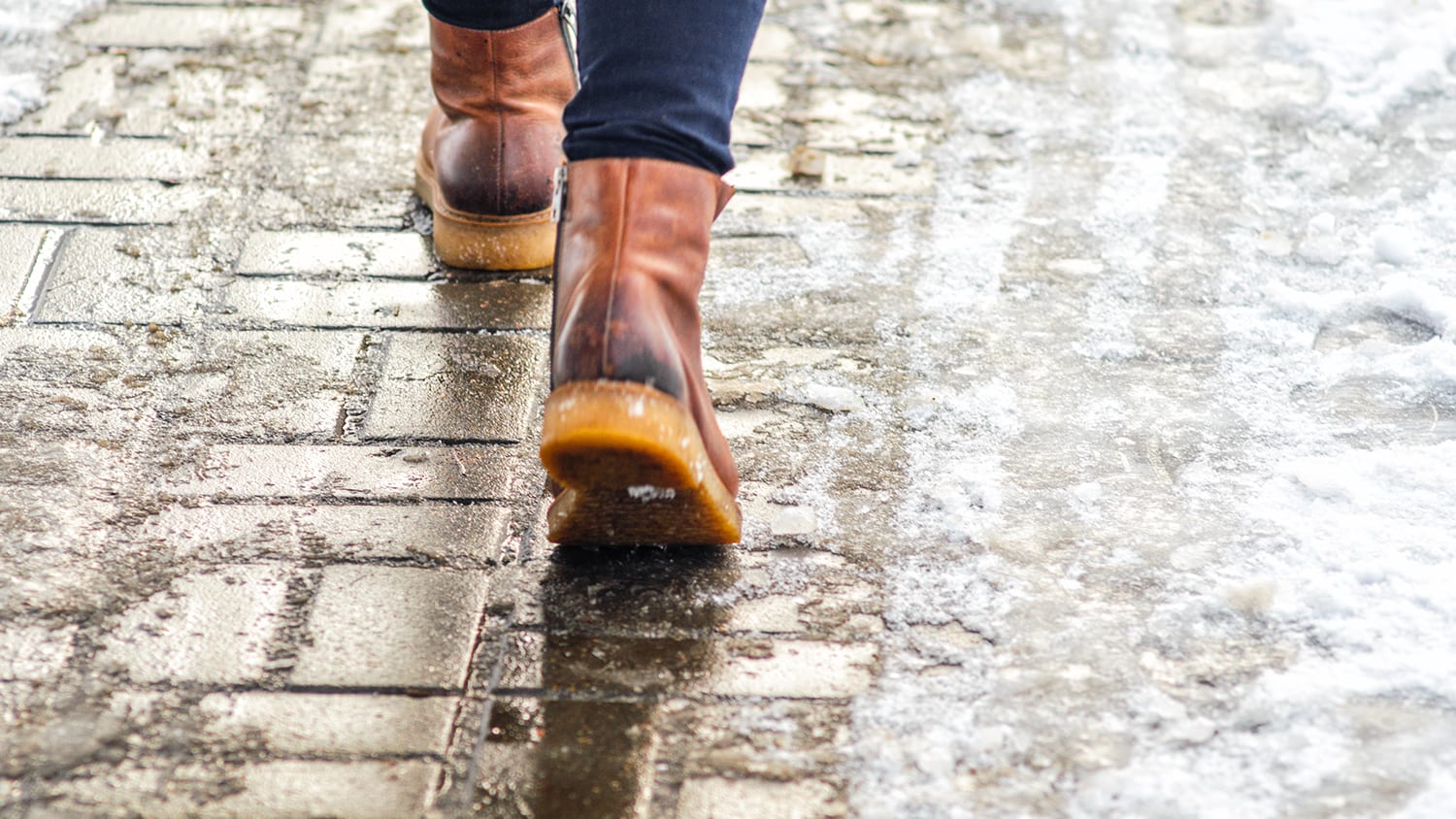 Person walking on pavement with melting snow