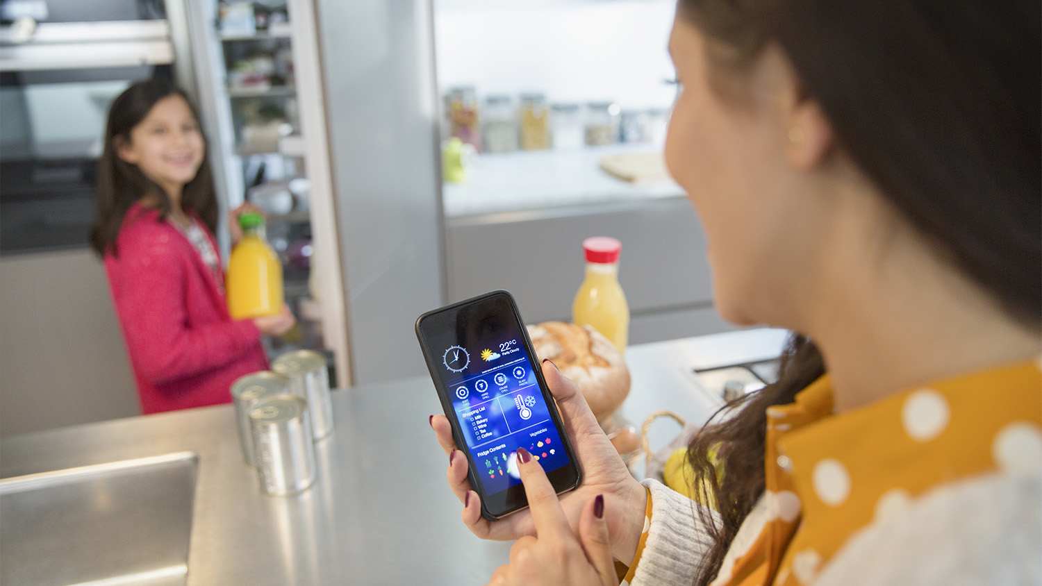 mother using phone to track groceries in fridge