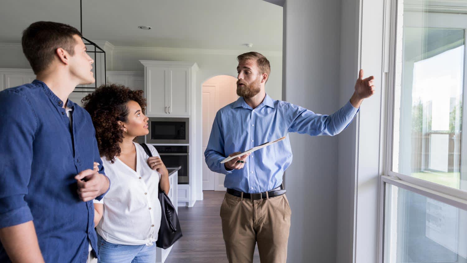 A man showing new home to a couple