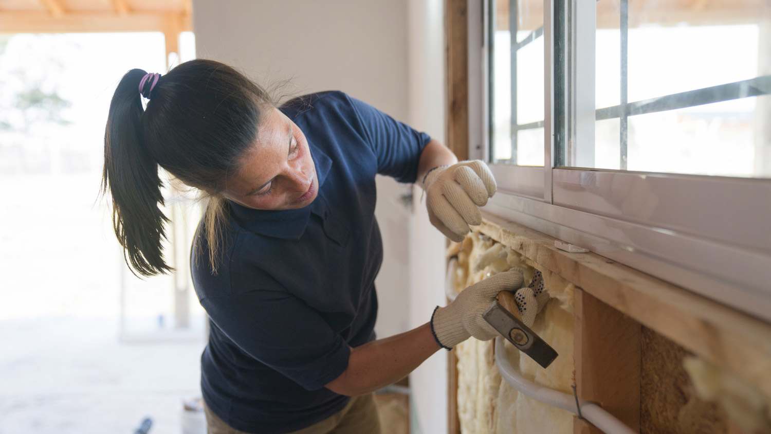 A worker installing fiberglass Insulation