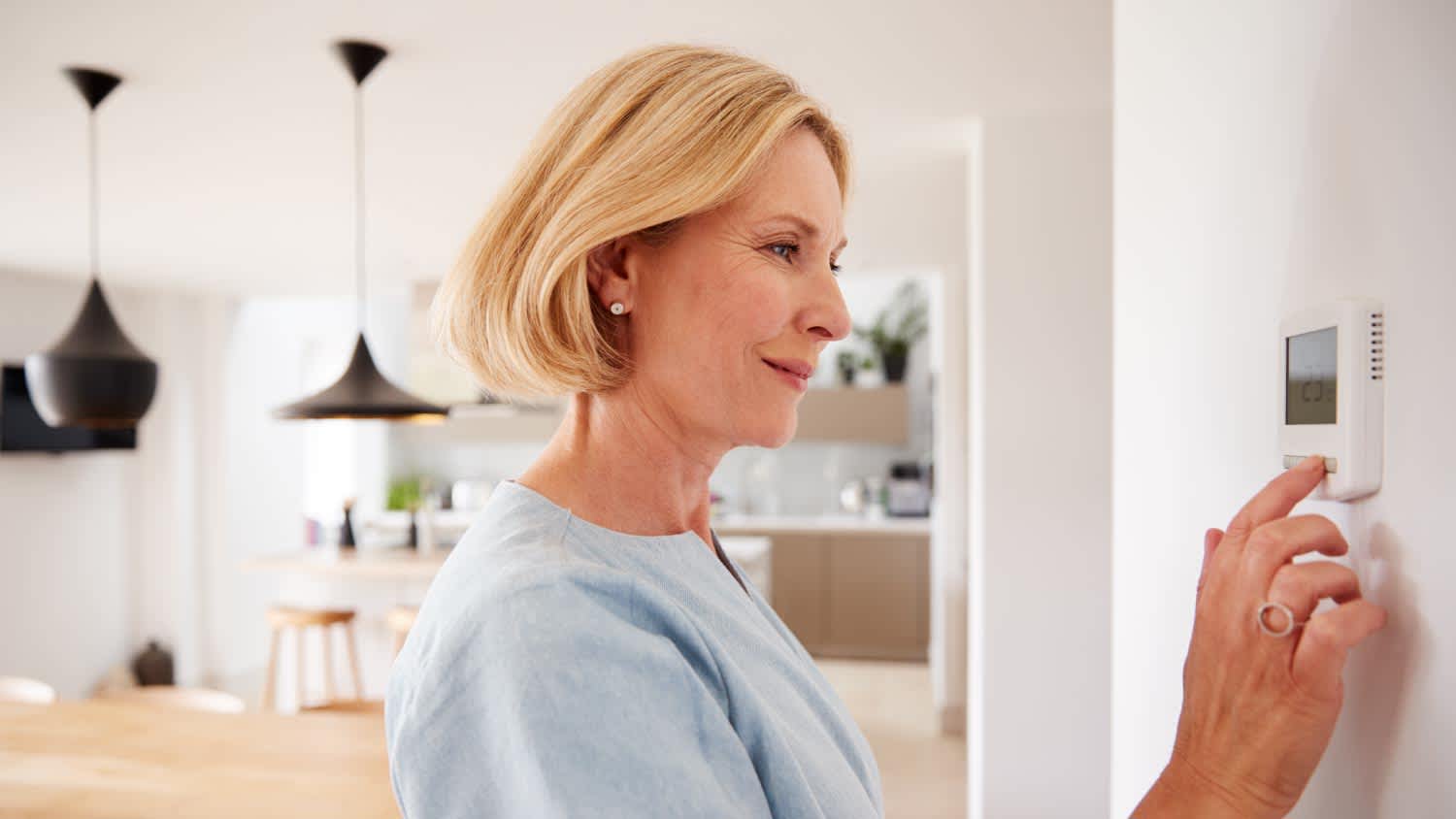 Woman adjusting central heating temperature