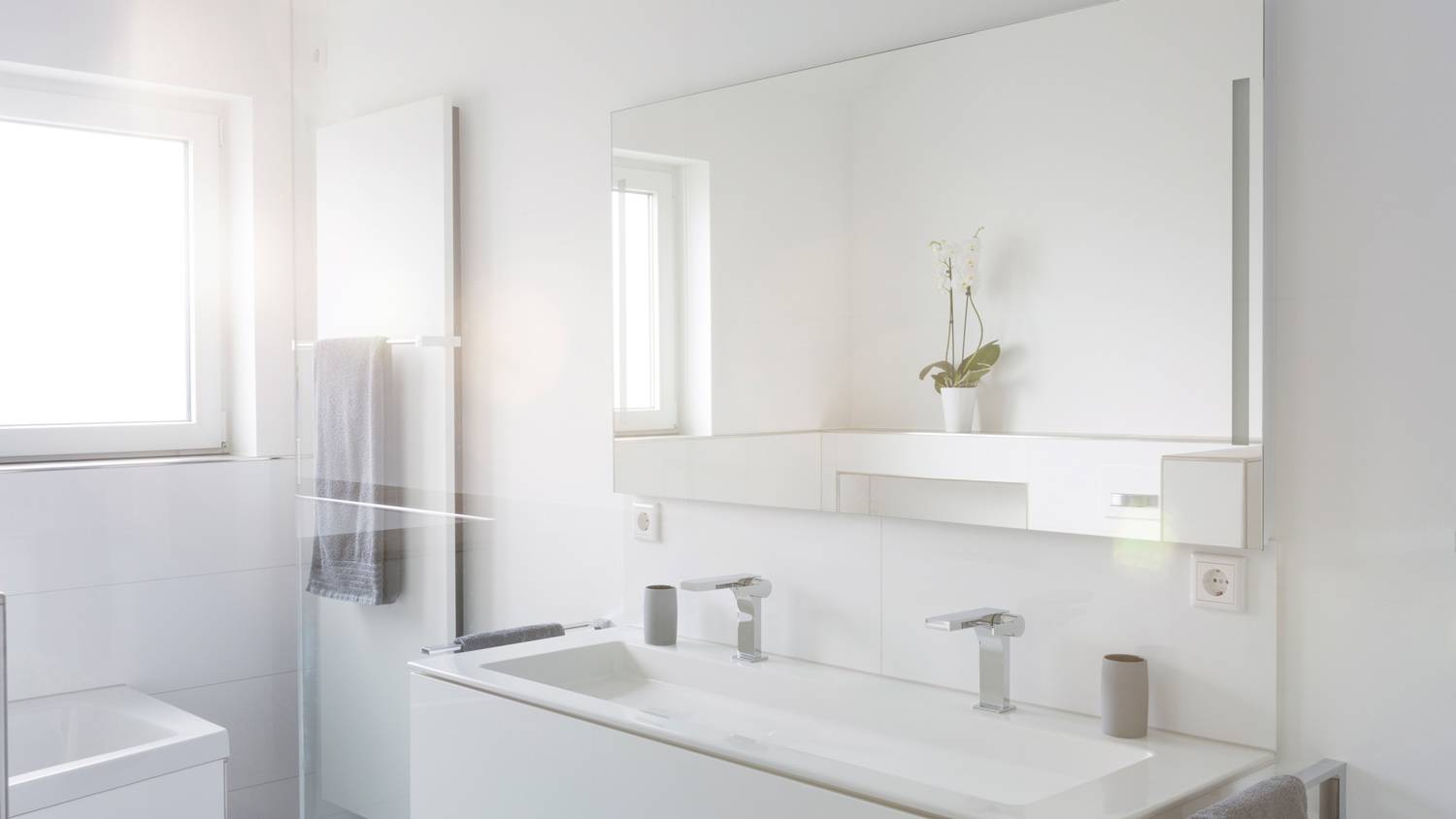 A modern white bathroom with a large mirror
