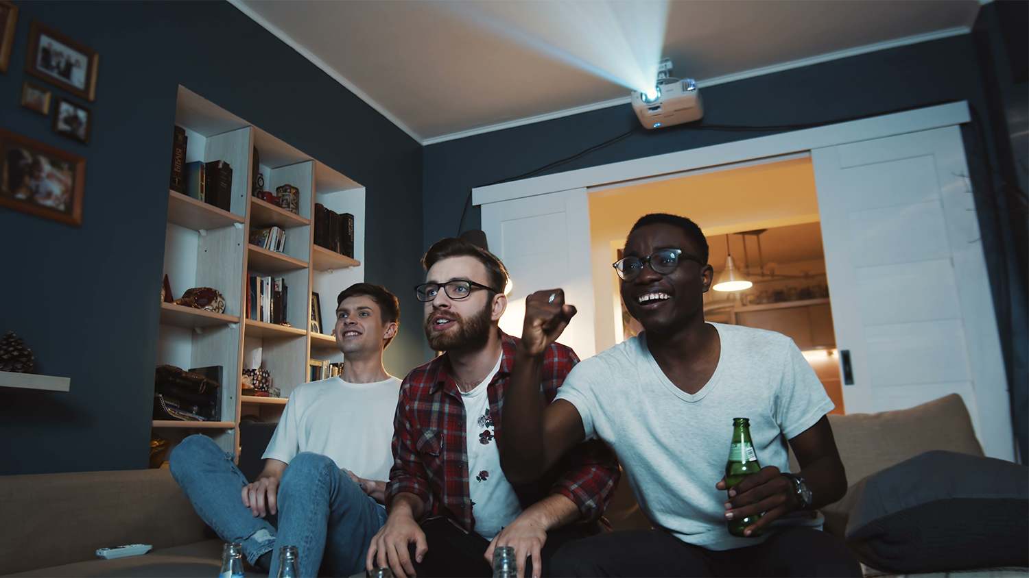 male friends watching sports game on projector