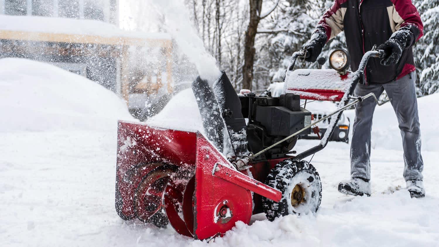 A man removing snow from house’s garden