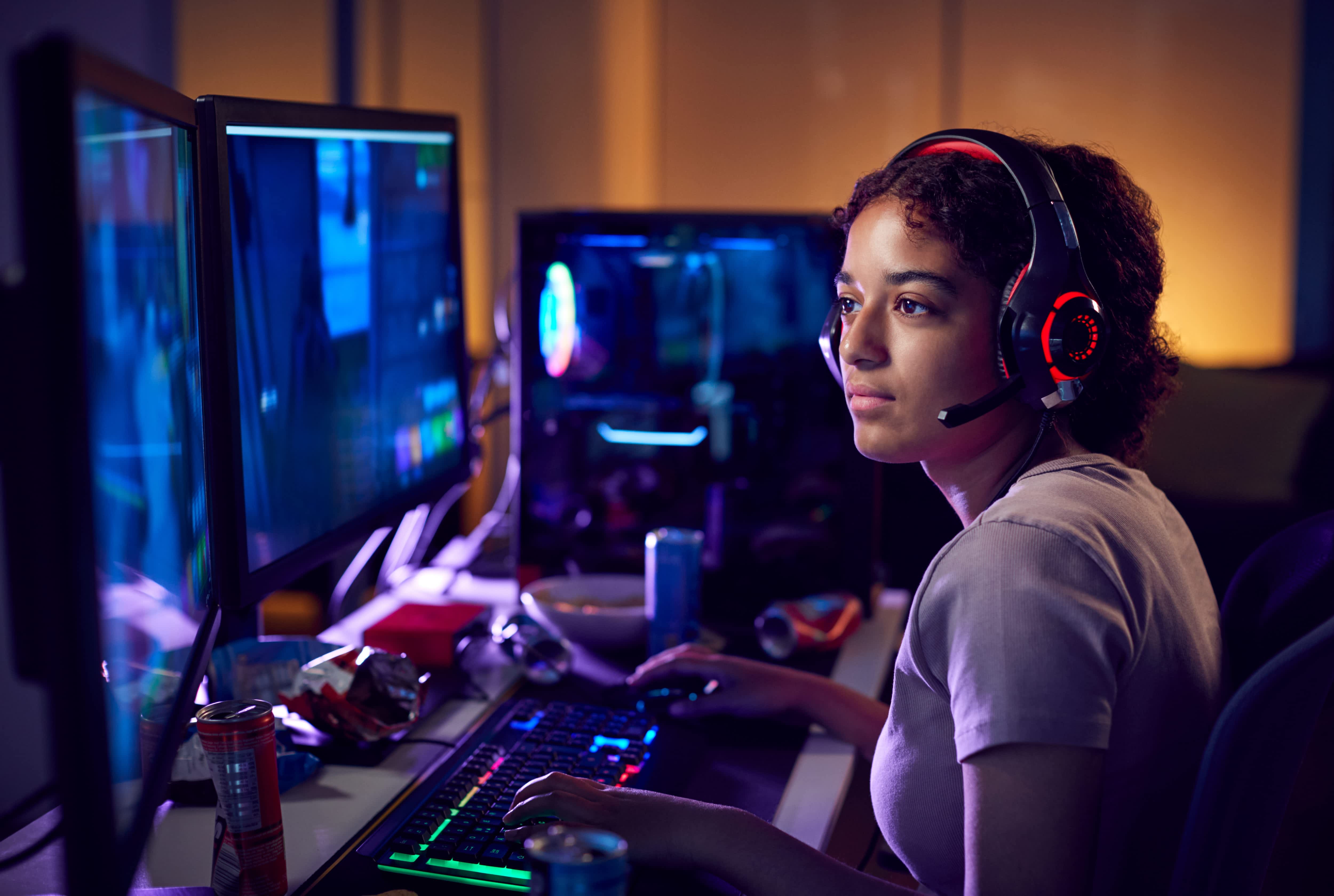 Teen gamer using dual computer screens in her bedroom