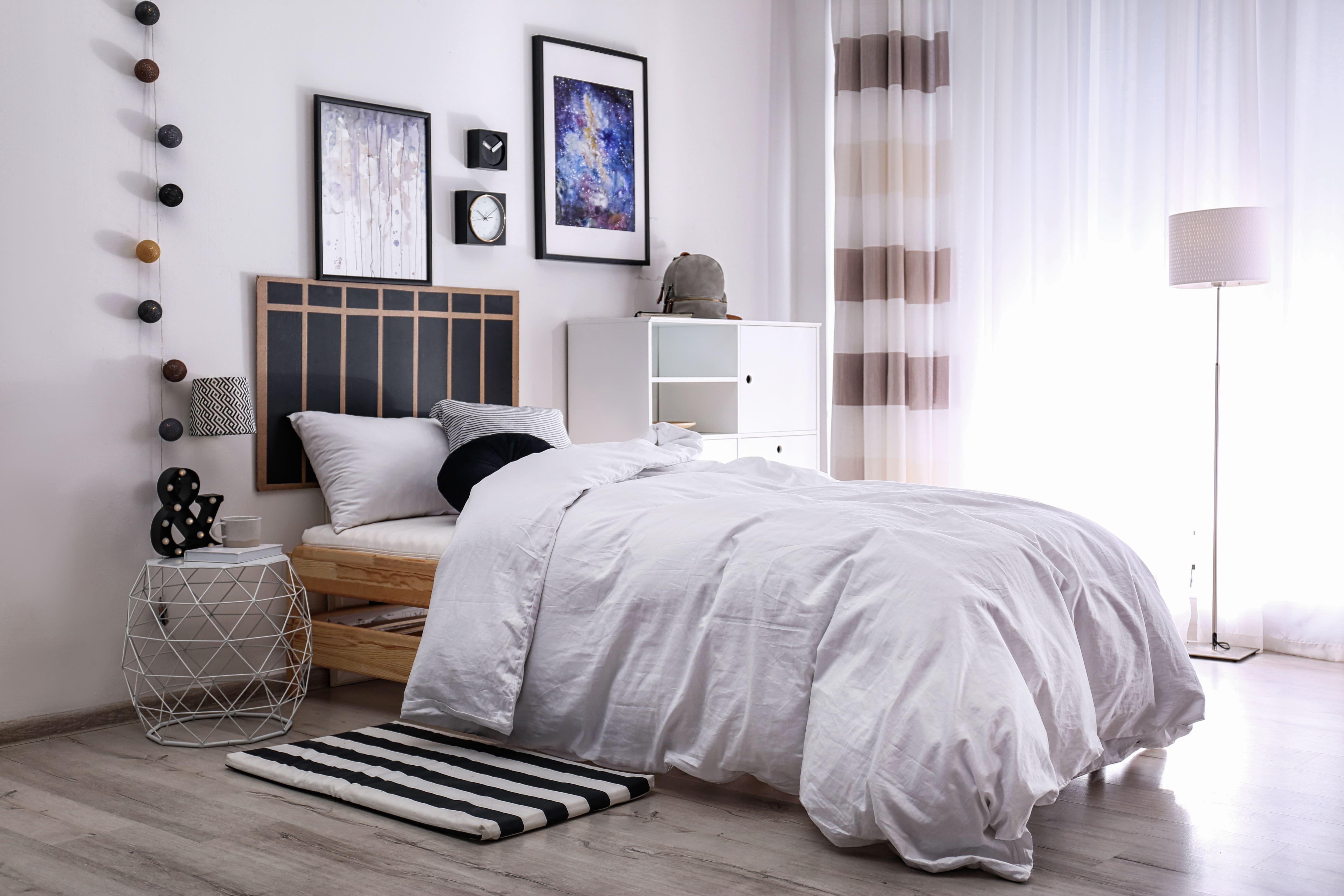 White teen bedroom with comfy twin bed, modern furniture, and ampersand sign, chalkboard, and ball garland decor