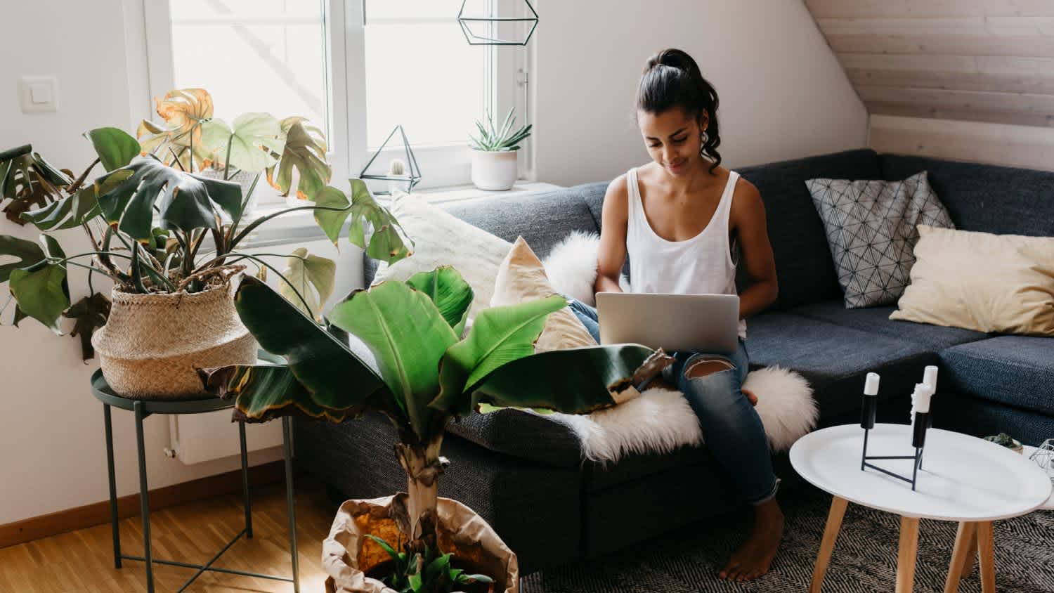 A woman sitting on the couch at home using laptop