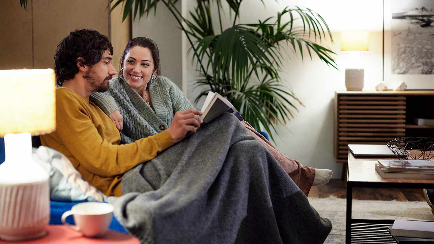 couple watching tv cuddled under blanket