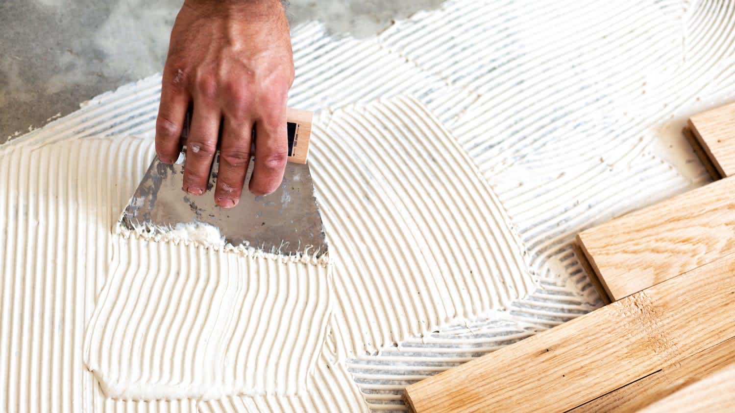 A professional applying glue on subfloor