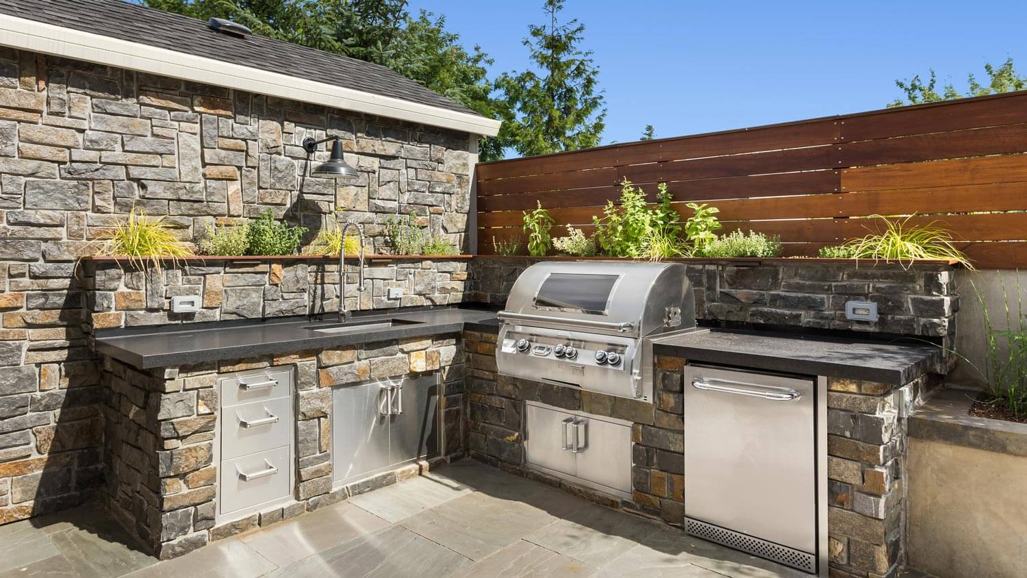 A stone outdoor kitchen with a built-in grill