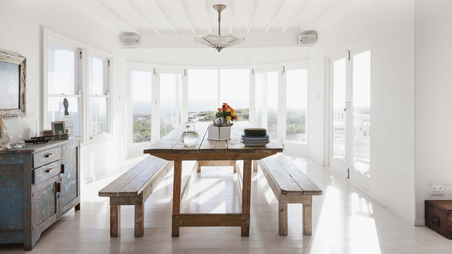 A wooden table and benches in a sunny dining room