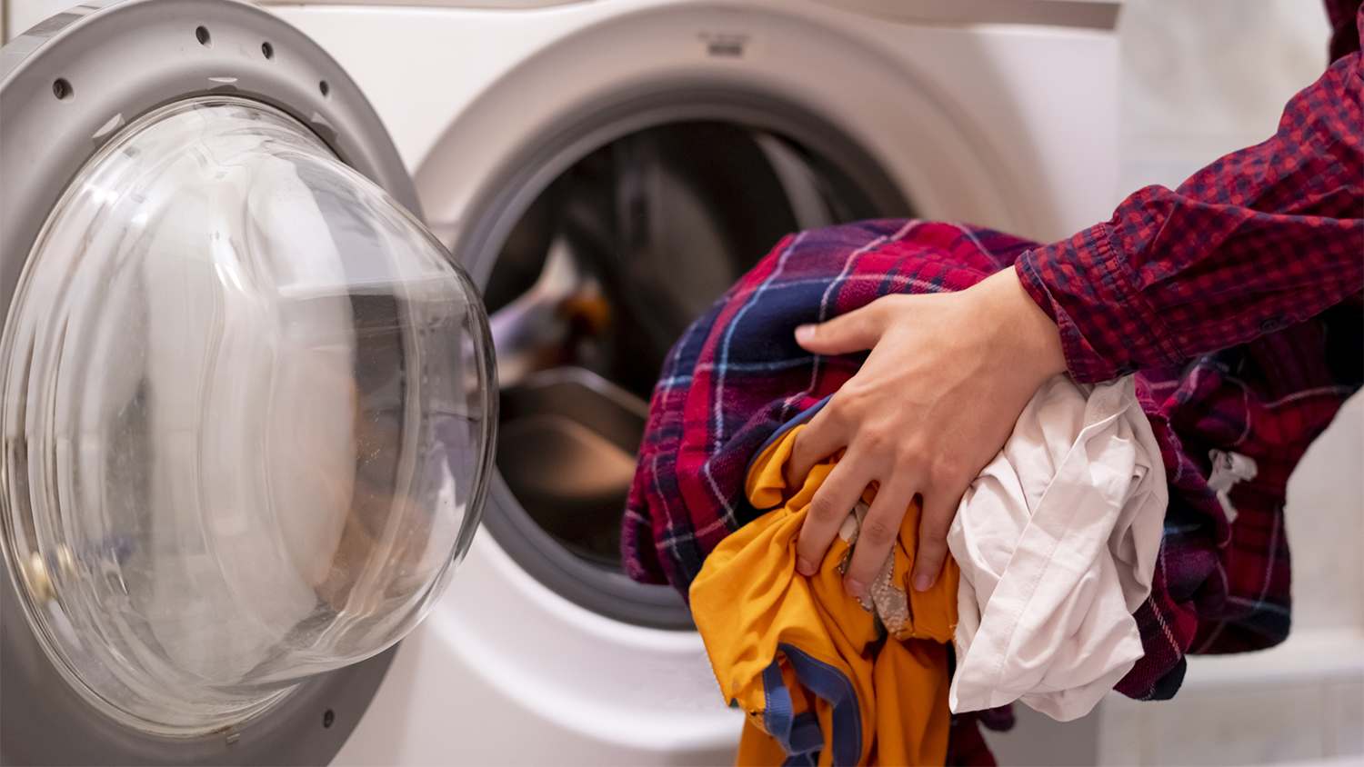 someone putting clothes into washer machine
