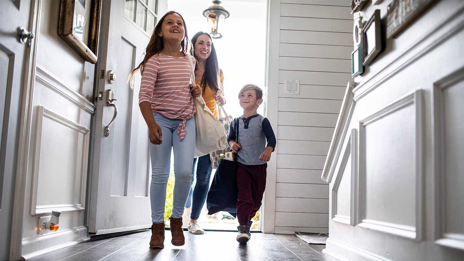 A family walks in the entry door of a nice house