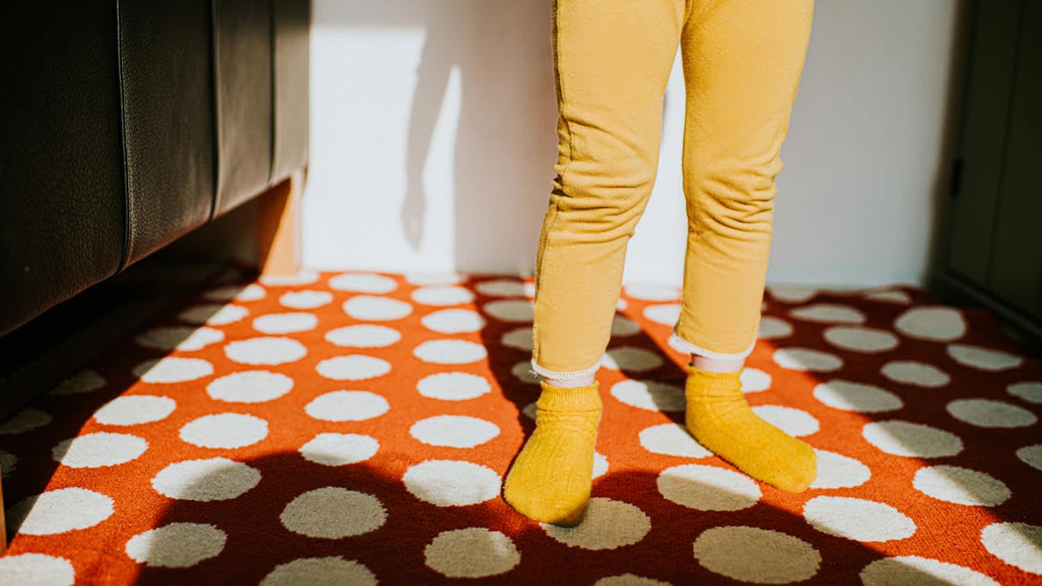 A kid in socks standing on a dotted carpet