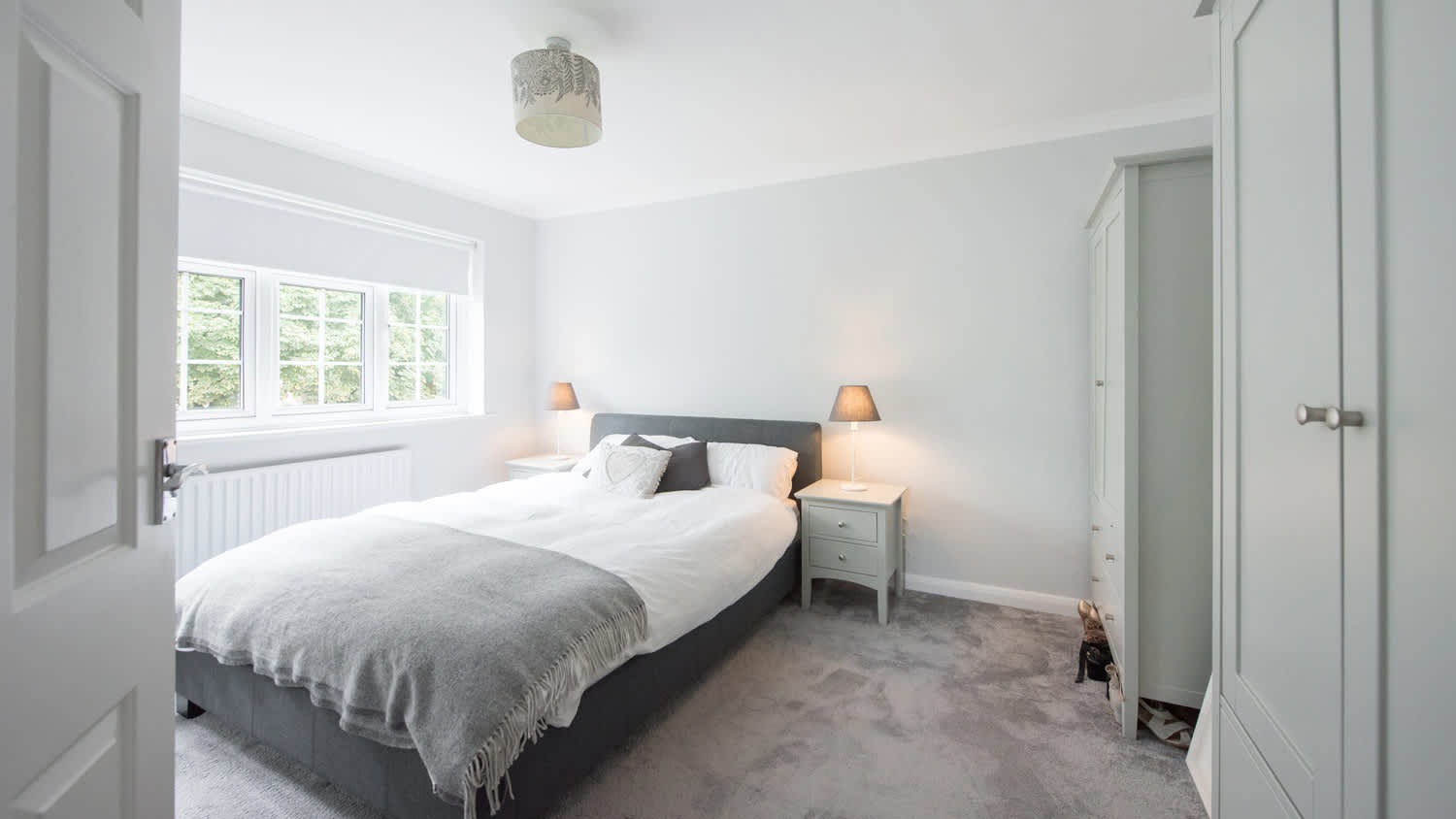 A spacious bedroom with grey carpeting