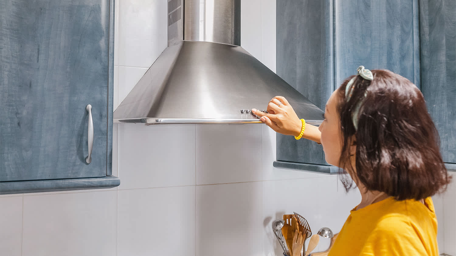 woman turning on exhaust vent in kitchen