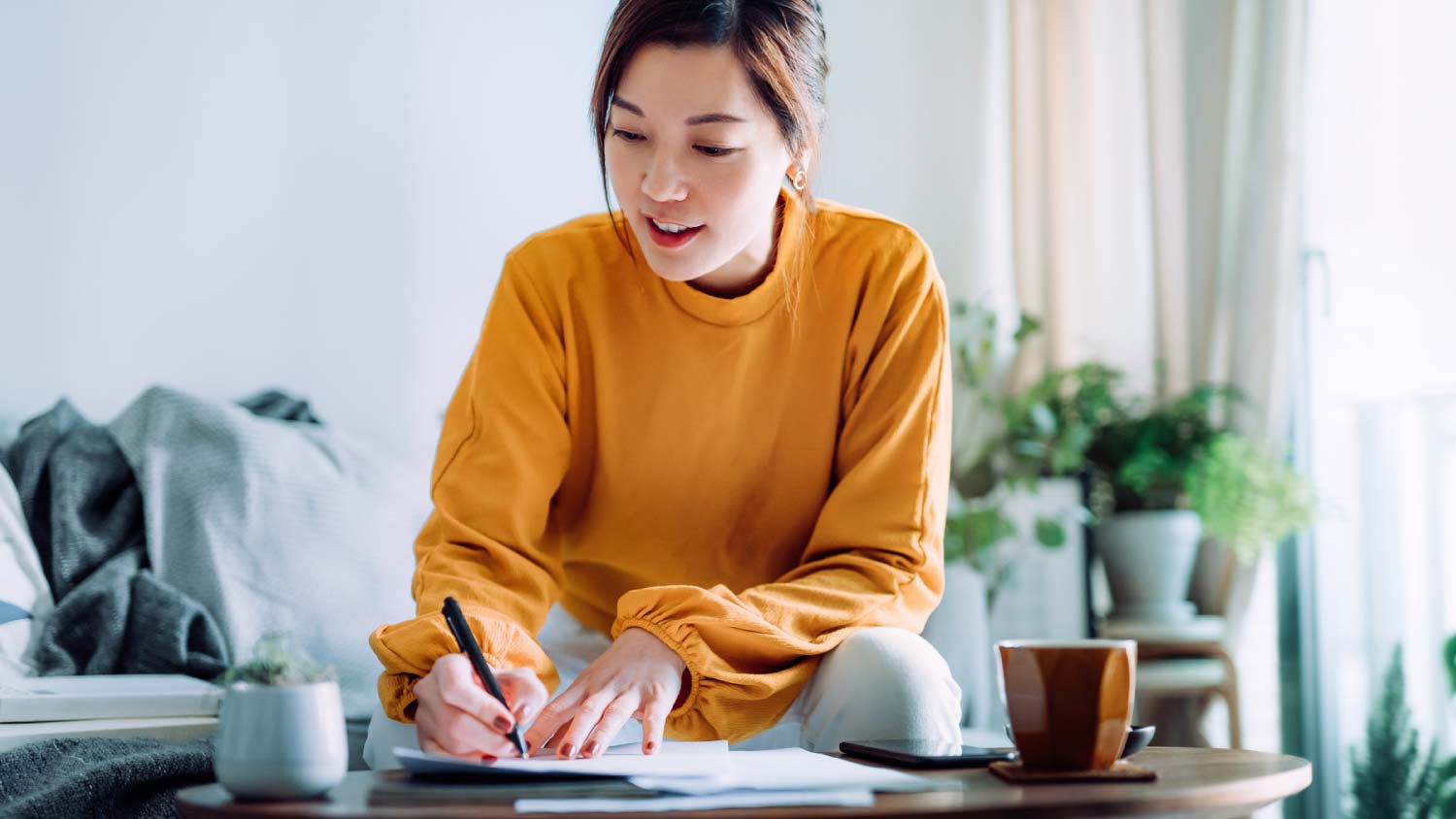 A young woman holding a pen and signing paperwork