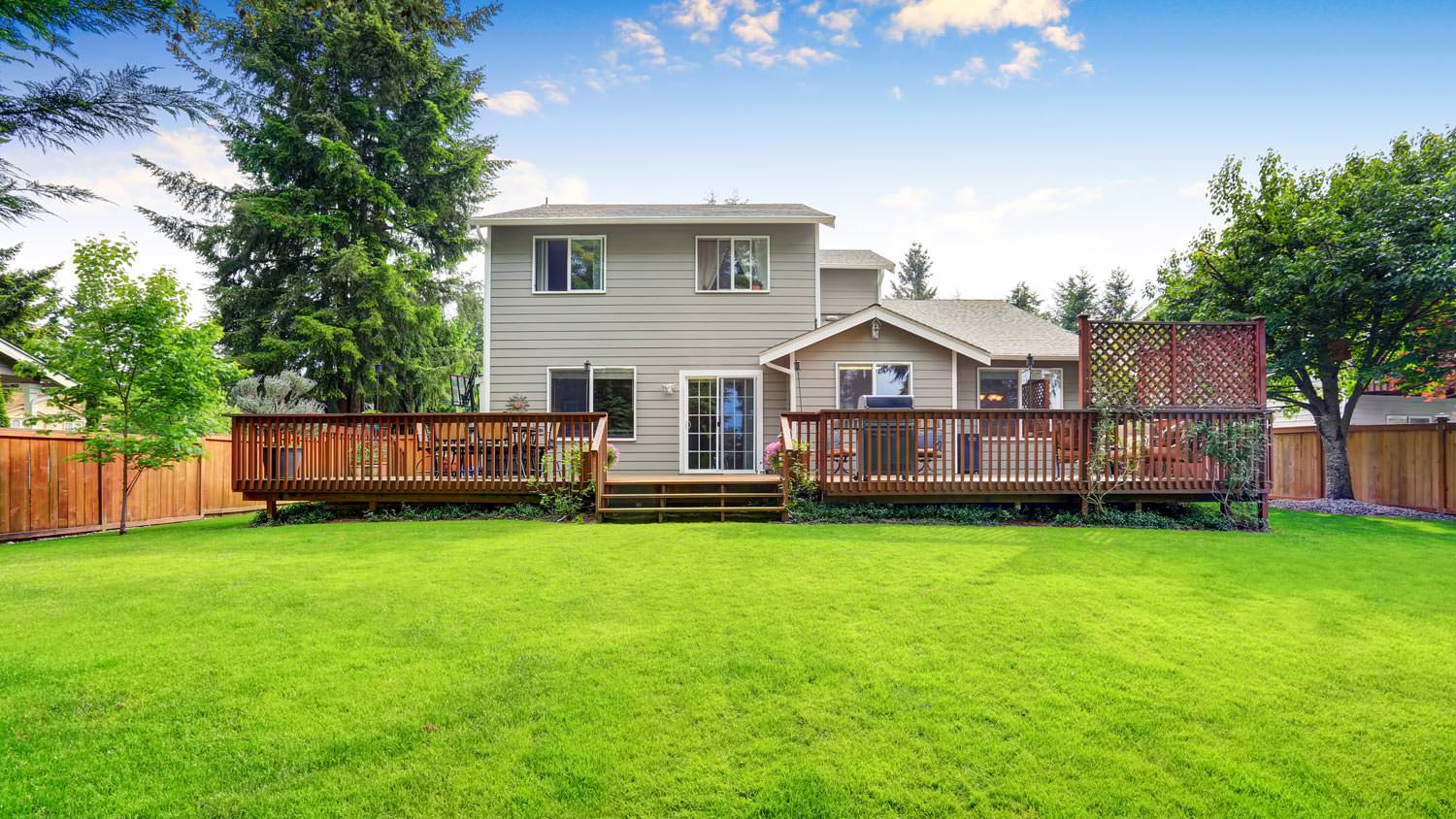 A wooden deck platform in the backyard of a house