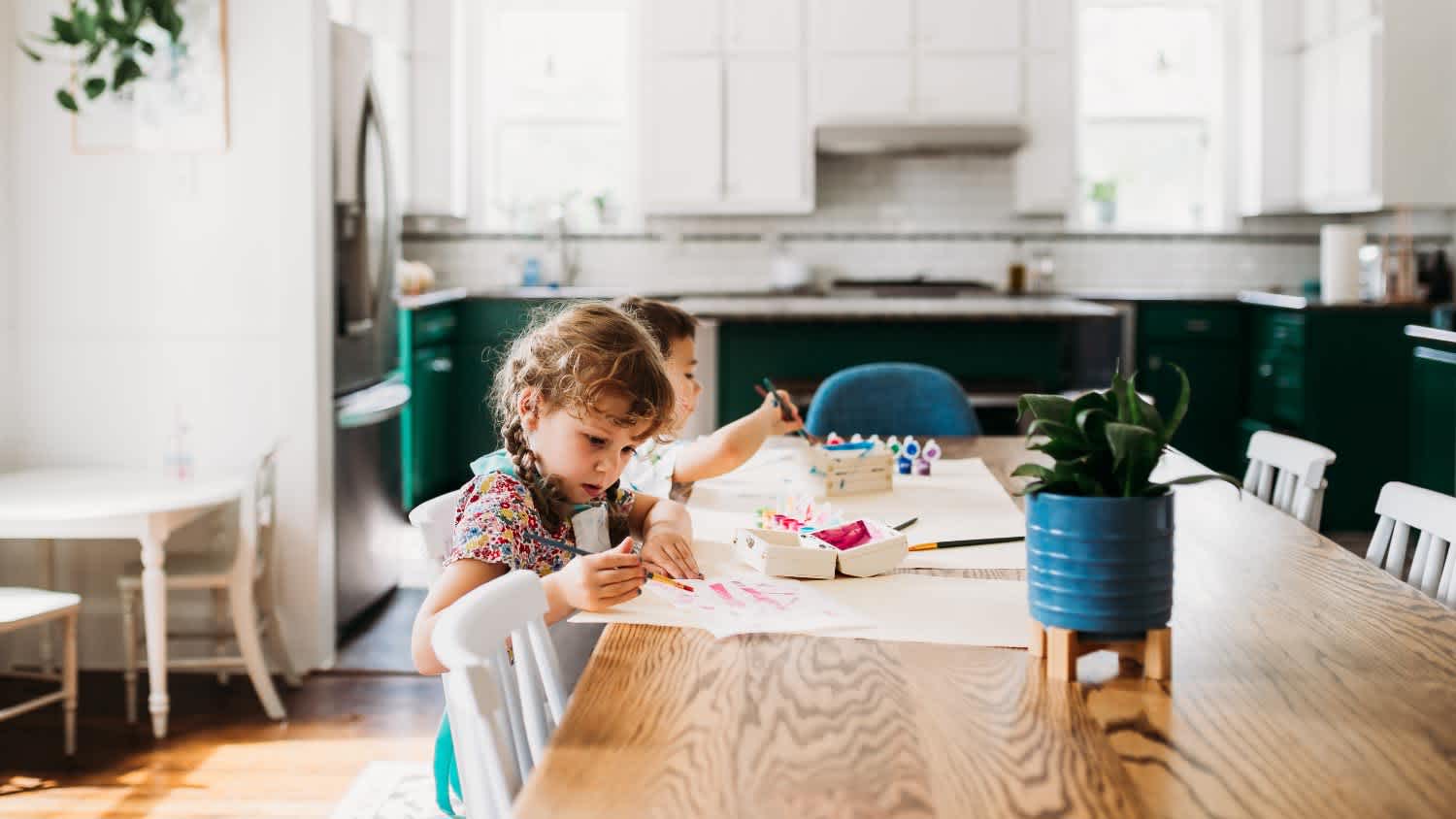 Two young kids doing arts and crafts in modern dining room